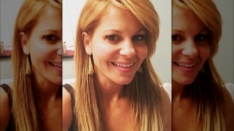 Candace Cameron Bure portant ses boucles d'oreilles Tiffany en maille dorée et souriante