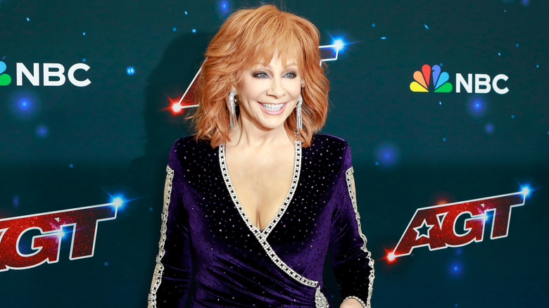 Reba McEntire posant dans une tenue violette avec un grand sourire