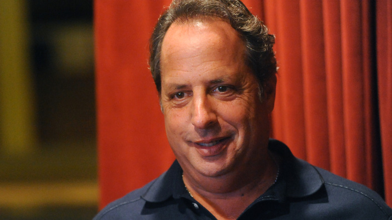 Jon Lovitz photographié devant des rideaux rouges