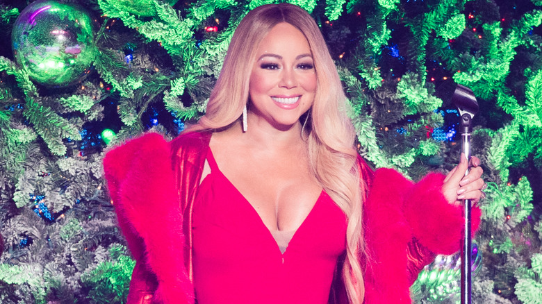 Mariah Carey chante dans une robe rouge devant un arbre