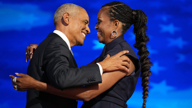 Barack et Michelle Obama rient ensemble sur scène.