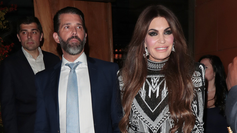 Donald Trump Jr. porte un costume avec une cravate bleue, Kimberly Guilfoyle porte une robe à motifs noir et blanc